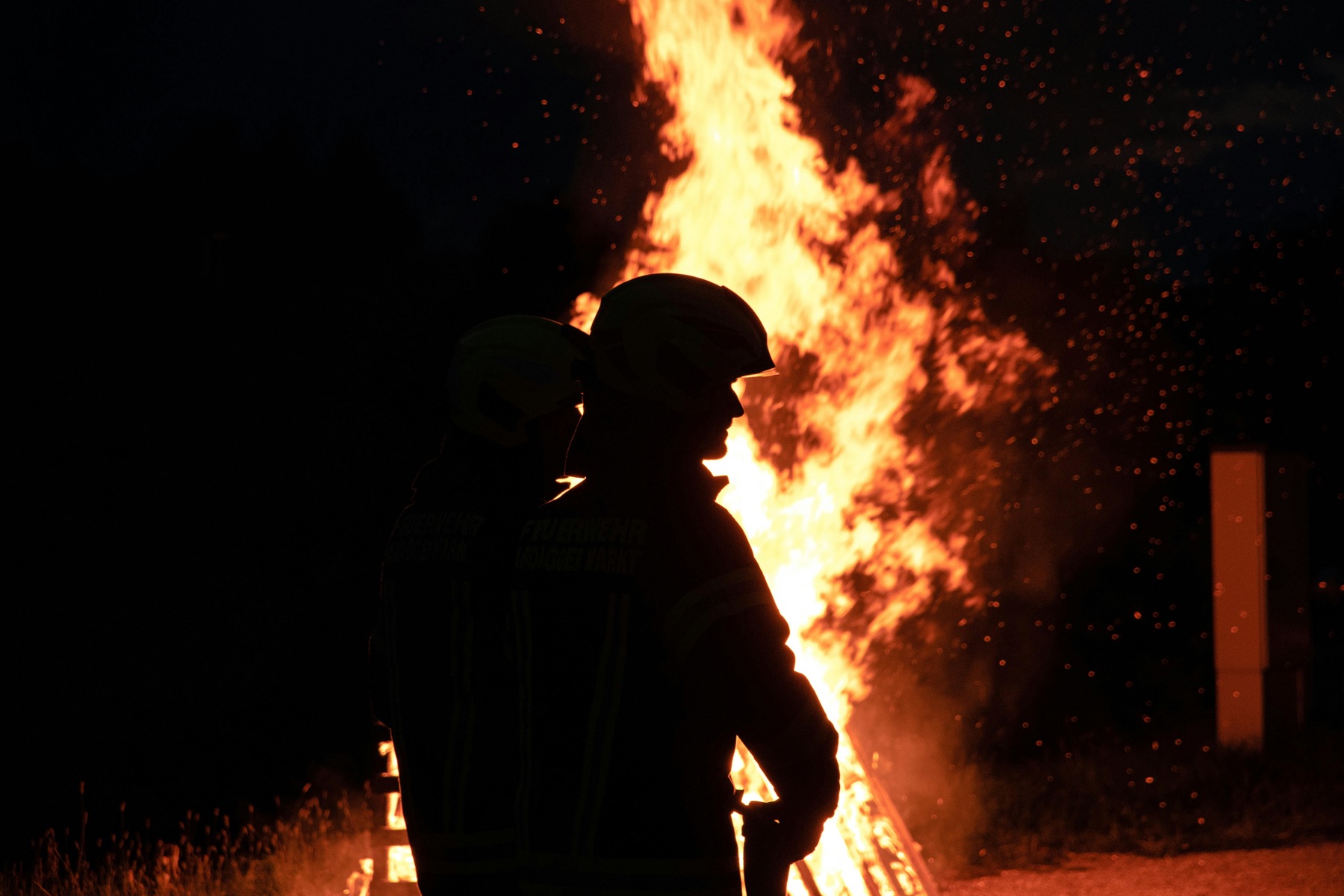 Feuerwehrmann in Atemschutzausrüstung vor großem Feuer